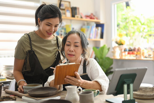 The pottery sales business of two grandmothers and granddaughter checking customer orders from the digital tablet.