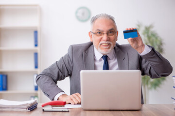 Old male employee holding credit card