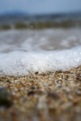 Fototapeta na wymiar Eine schaumige Welle am Strand von Sardinien
