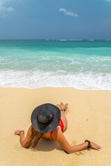 Fototapeta na wymiar Woman with reb swimsuit and black hat at the beach in Bali indonesia
