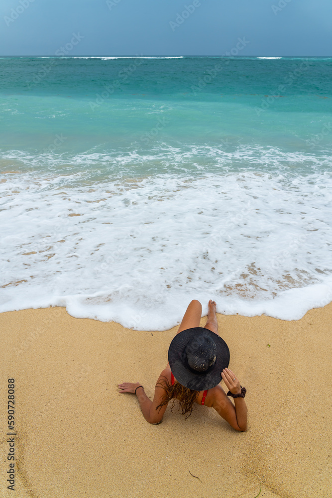 Poster Woman with reb swimsuit and black hat at the beach in Bali indonesia