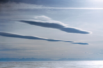 Clouds over a frozen airship-shaped lake at sunset.