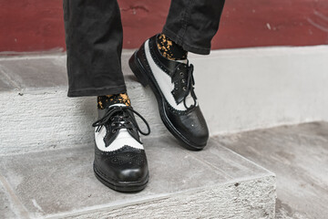 The young man wore a classic two-tone genuine leather brogue, vintage brogue wingtips that were shiny and ready to hang out on a sunny day.