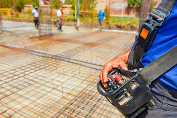 Worker is holding remote, wireless, control for concrete pump at building site © Roman_23203