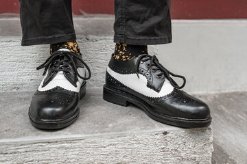 The young man wore a classic two-tone genuine leather brogue, vintage brogue wingtips that were shiny and ready to hang out on a sunny day.