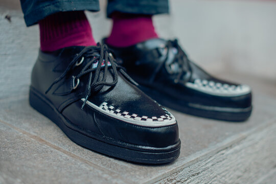 Young man sitting and wearing black genuine leather creepers sneakers. These casual yet elegant shoes are handmade by an at-home shoemaker, perfect for hanging out on a sunny day