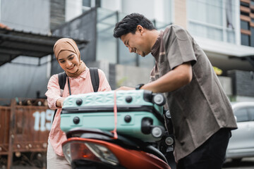 happy asian muslim couple pack his suitcase on motorbike travel during eid mubarak back to hometown
