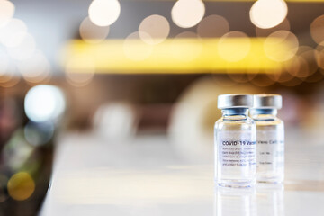 Bottle or vials of vaccine or drugs with blur background and bokeh.Scientists use technology to make covid 19 vaccination for virus.Medicine on white table with light reflection.Pharmacy and Medical.