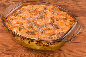 Baked vegetable casserole with salmon slices in glass baking dish