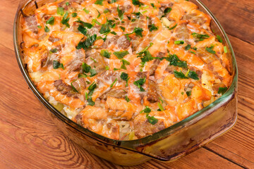 Vegetable casserole with salmon slices with greens in baking dish