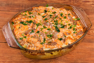 Vegetable casserole with salmon slices with greens in baking dish