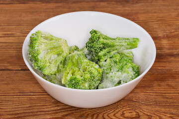 Frozen broccoli in white bowl on the rustic table
