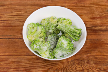 Frozen broccoli in white bowl on the rustic table