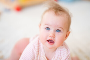 Portrait of charming Caucasian baby toddler with blue eyes in home in children room