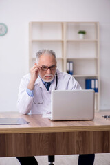 Old male doctor working in the clinic