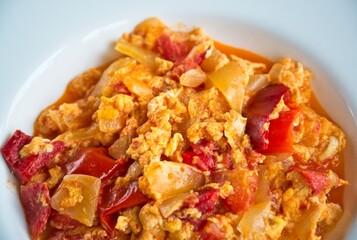 Close up of a typical hungarian homemade lecso (in hungarian: lecsó) from tomatoes, peppers, onions and eggs on white plate.  