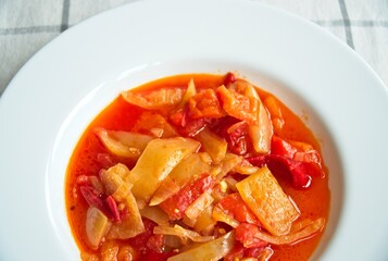 Close up of a typical hungarian homemade lecso (in hungarian: lecsó) from tomatoes, peppers and onions on white plate.   