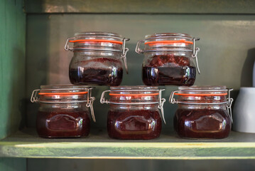 Jars with homemade jam on a wooden shelf in a row