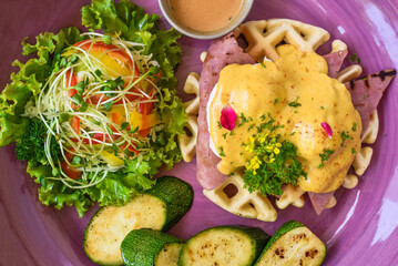 Eggs Benedict (poached eggs) on grilled ham with holland sauce on belgian waffles with grilled...