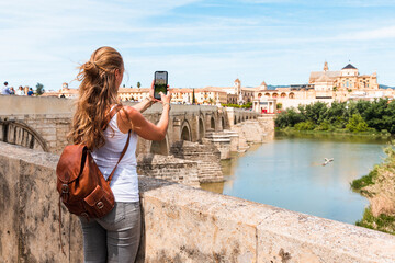 Woman taking photography with smartphone the view of Cordoba city - Spain, Andalusia - obrazy, fototapety, plakaty