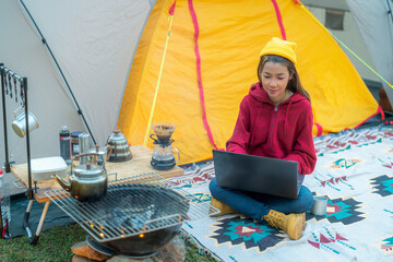 Woman working drink a coffee and working with computer note book between tent camping