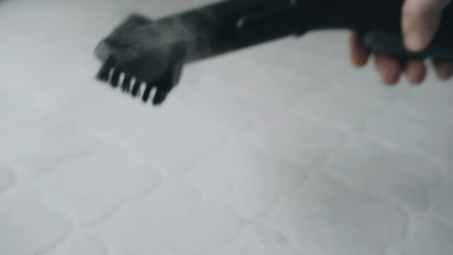 Close-up. Cleaning the mattress with a steam cleaner. Heat treatment and cleaning from dirt and insects of bedding.
