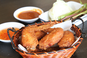Fried chicken wings served in a brown basket on the table, selective focus 