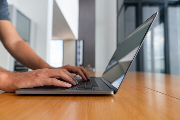 Man hands typing on the laptop keyboard on wooden desk