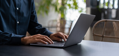 Businessman hands typing on laptop keyboard on table