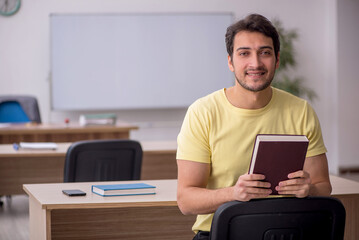 Young male student teacher sitting in the classroom