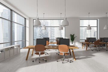 Light office interior with pc computer on desk in row and sideboard, window