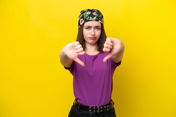 Young Ukrainian woman isolated on yellow background showing thumb down with two hands