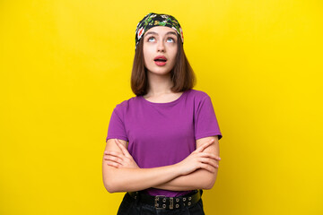 Young Ukrainian woman isolated on yellow background looking up and with surprised expression