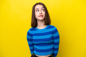 Young Ukrainian woman isolated on yellow background and looking up