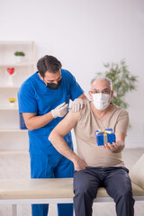 Young male doctor giving giftbox to old male patient