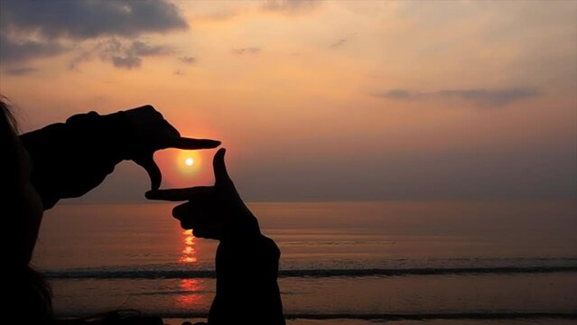 The woman making frame round the sun with her hands in sunrise,Future planning idea concept.	