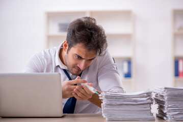 Obraz premium Young male employee and too much work in the office