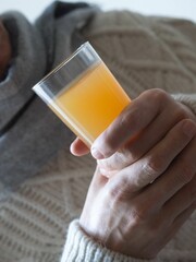 Vertical shot of a man drinking a cup of orange juice