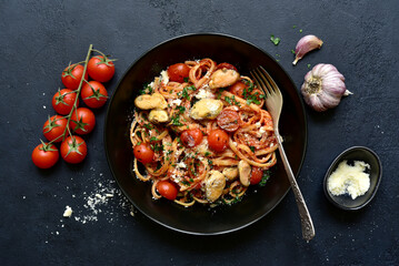 Pasta with mussels and grilled tomato in spicy sauce. Top view with copy space.