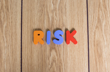 Colorful cubes lettering word "RISK" on wooden background. 