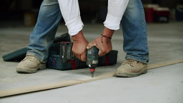 Beautiful view of an hardworking constructor using a drill for  making a building