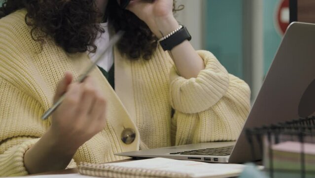 Close-up Shot Of Hands Of Nervous Unrecognizable Woman Sitting At Desk In Office, Talking On Mobile Phone, Gesticulating, Fidgeting With Pencil, And Using Laptop Computer