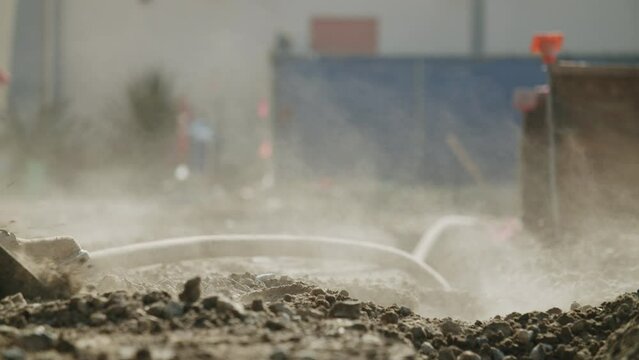 Closeup of the construction sand and soil and a builder digging it with a special shovel