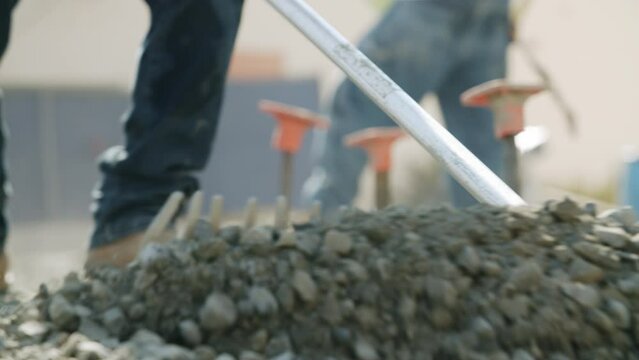 Closeup of the construction sand and soil and a builder digging it with a special shovel