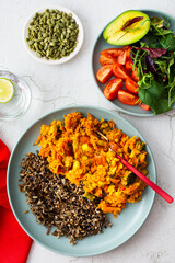 Healthy lunches, wild rice with carrot and tomato gravy, broccoli and onion, fresh mixed salad with pumpkin seeds, water with lemon, top view