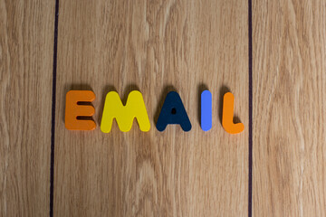 closeup shot colorful letter cube spelling "EMAIL". Letter blocks of "EMAIL" on brown wooden background. 