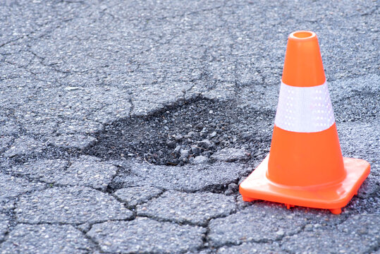 Ein Leitkegel und Schlagloch in einer Straße