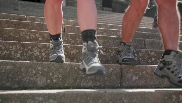 Slow-motion of two senior wearing hiking shoes and going down the stairs