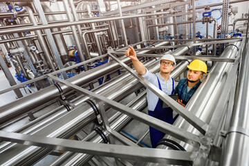 Two young engineers inspect an industrial plant for the treatment of contaminated water. Top view on engineering structures. Factory workers solve problems.