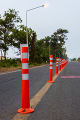 A low-angle view of many reflective orange plastic poles set up as a sign to prevent oncoming traffic.